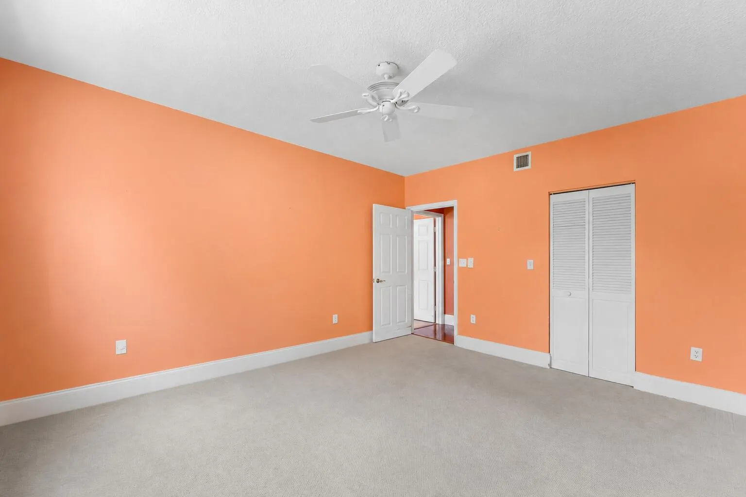 Room featuring orange walls, white trim, and light-colored carpet flooring