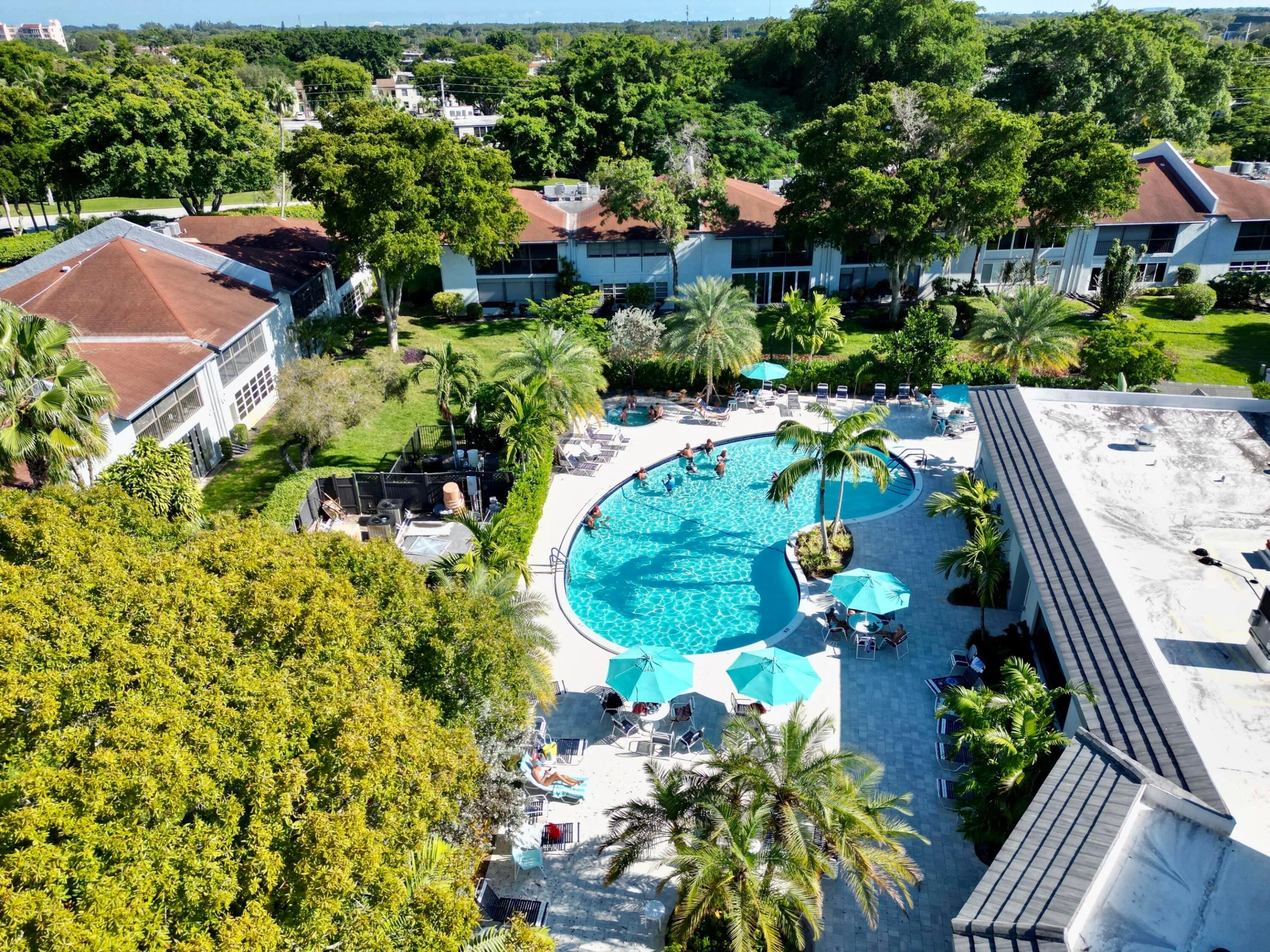 Resort-style pool area featuring a freeform swimming pool, surrounding lounge seating, and several shade umbrellas