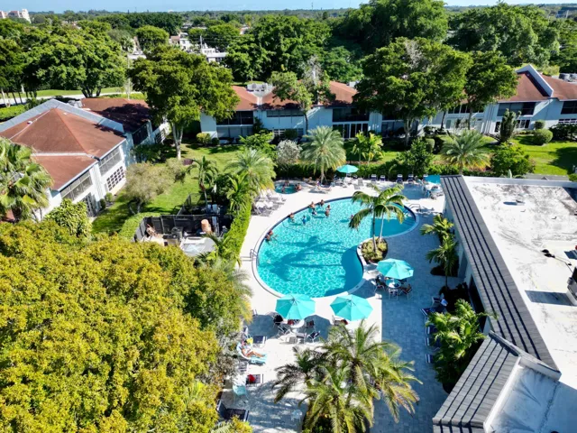 Resort-style pool area featuring a freeform swimming pool, surrounding lounge seating, and several shade umbrellas