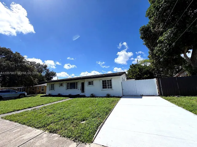 White exterior with multiple windows, concrete driveway, and a fenced side yard