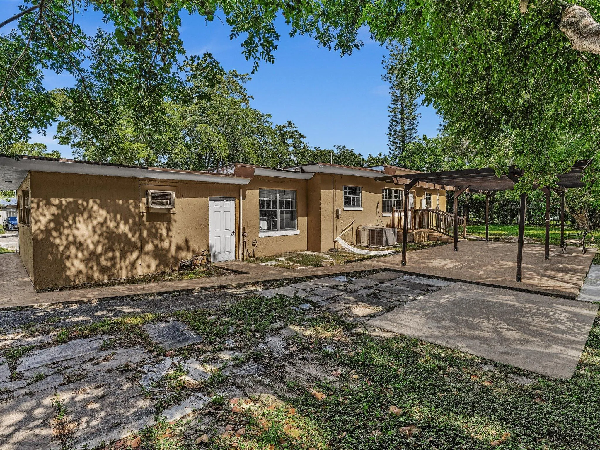 Exterior featuring stucco siding, multiple windows with grilles, and a white entry door