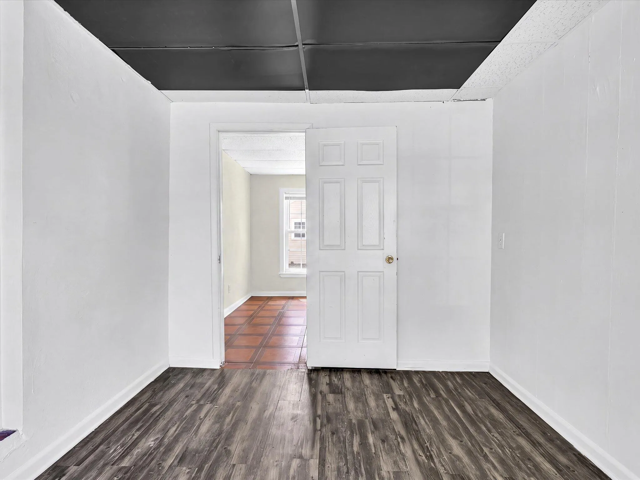 Room featuring wood-finish flooring, white walls, and a black ceiling