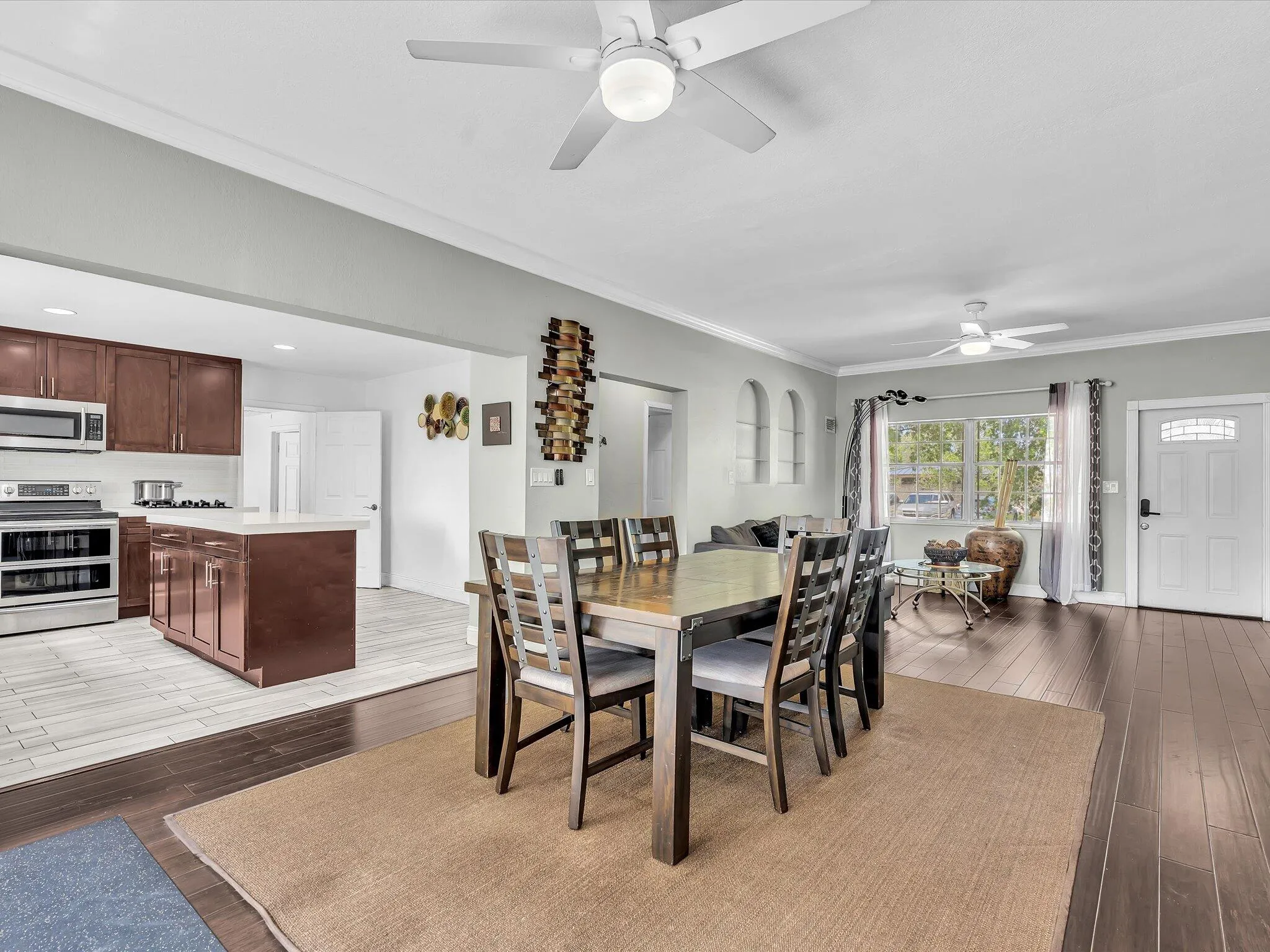 Open concept living space featuring rich wood-finish flooring and crown molding