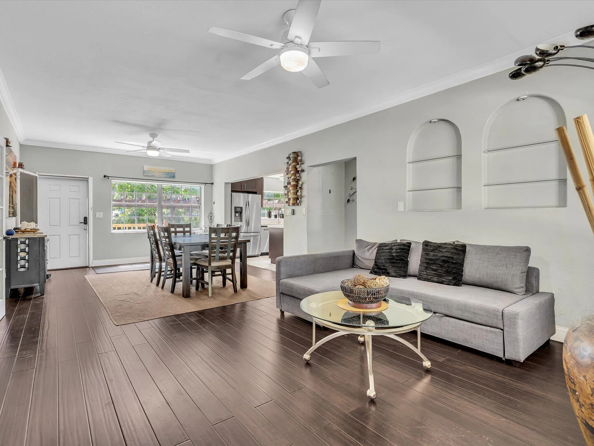 Open-concept living area featuring wood-finish flooring, recessed wall niches, and ceiling fans