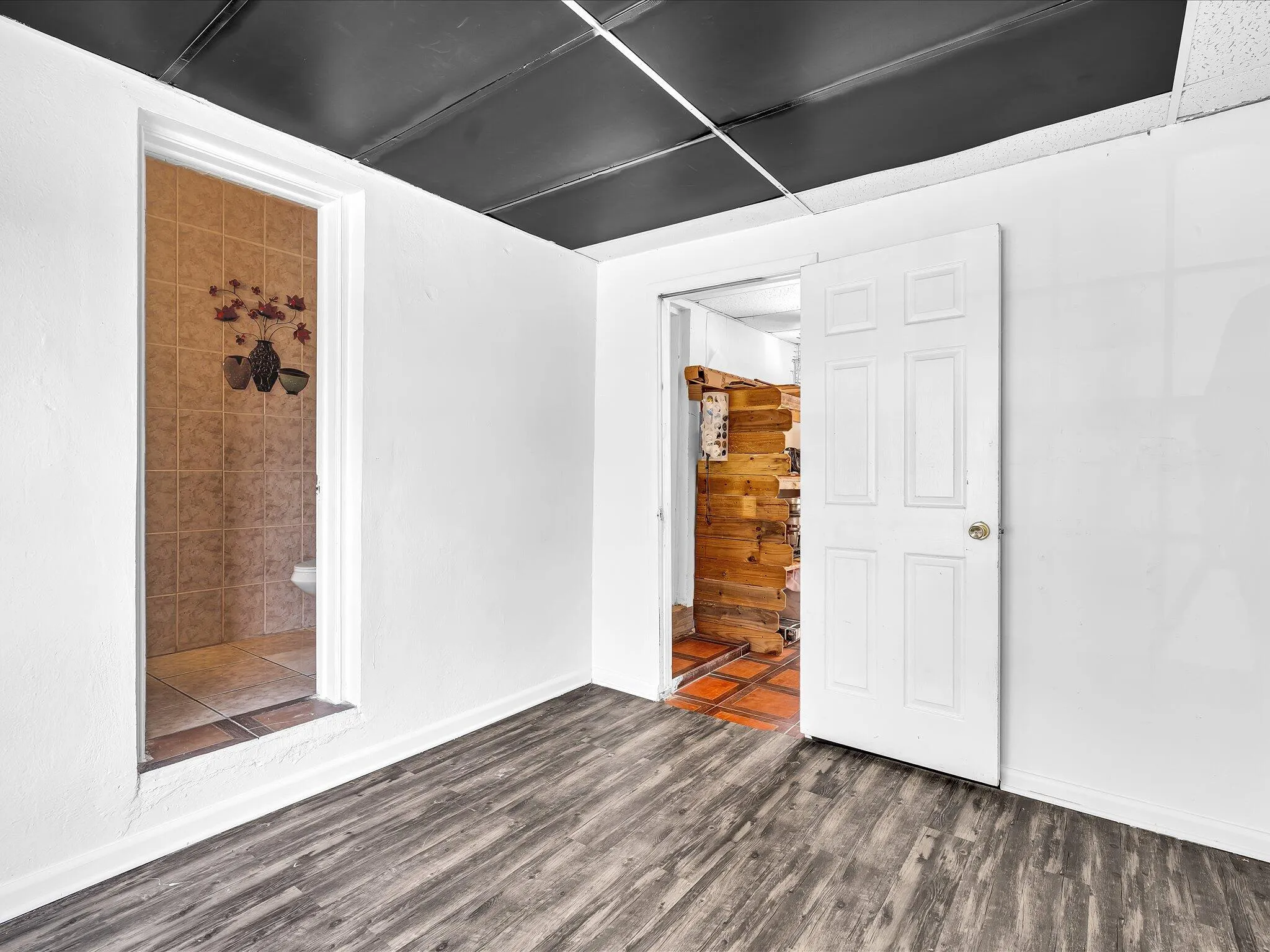 Spacious room featuring wood-finish flooring and white walls