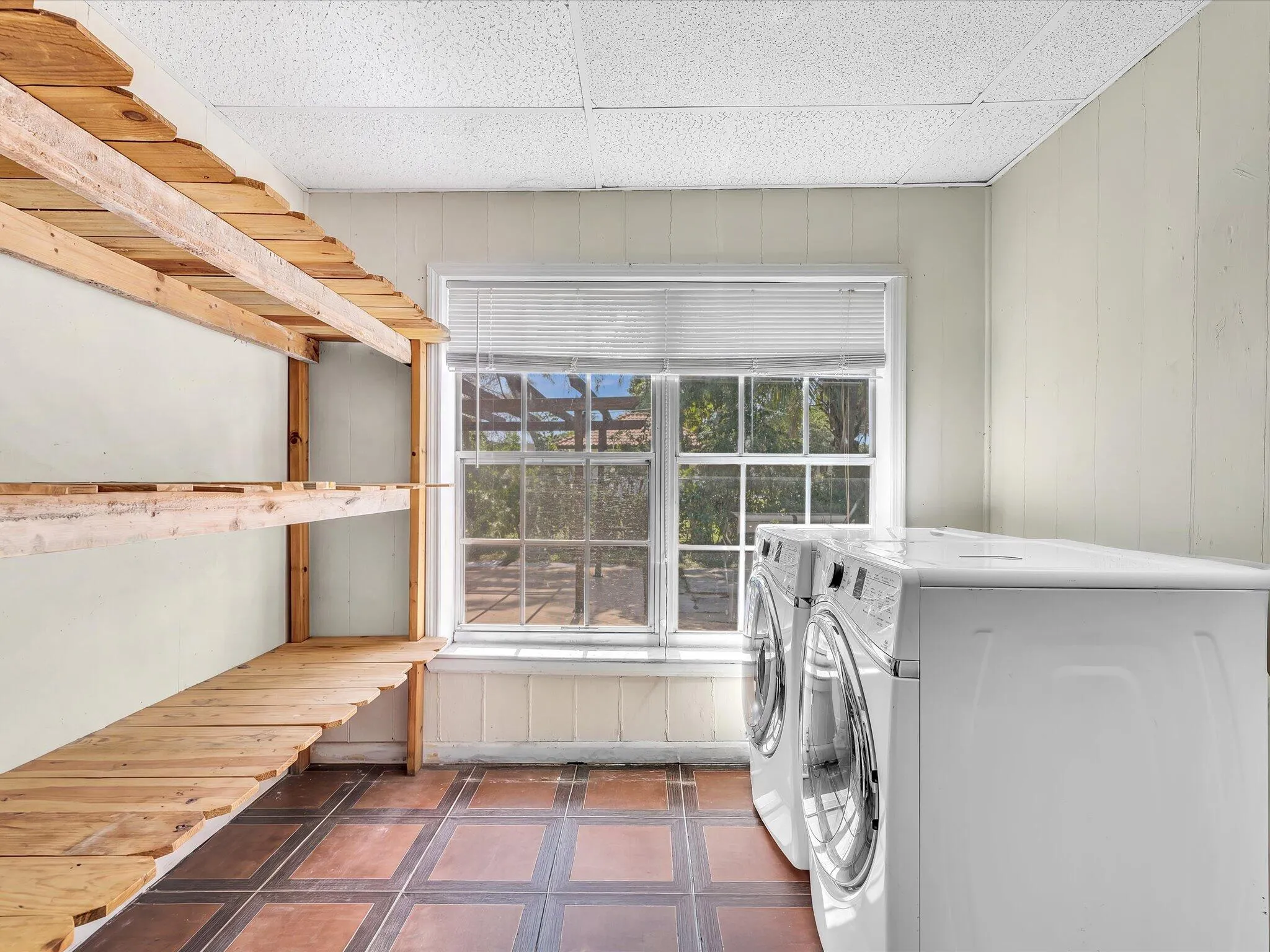 Utility area with extensive wood shelving and terracotta-style floor tiling
