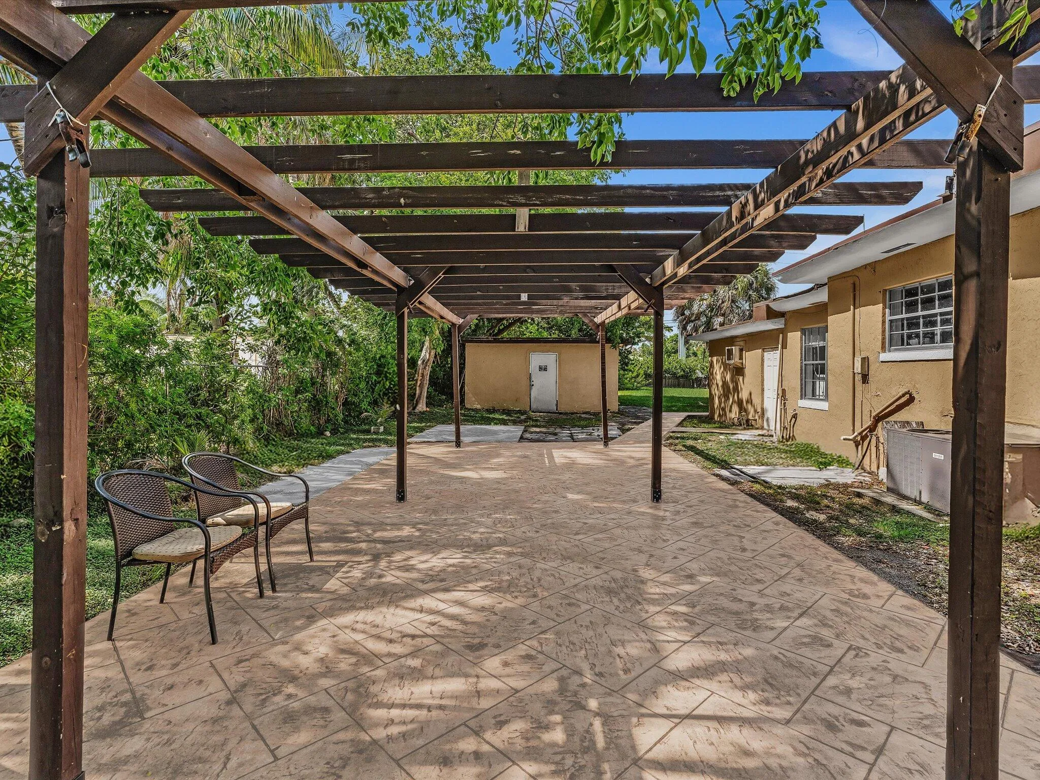 Expansive stamped concrete patio featuring an overhead wood pergola