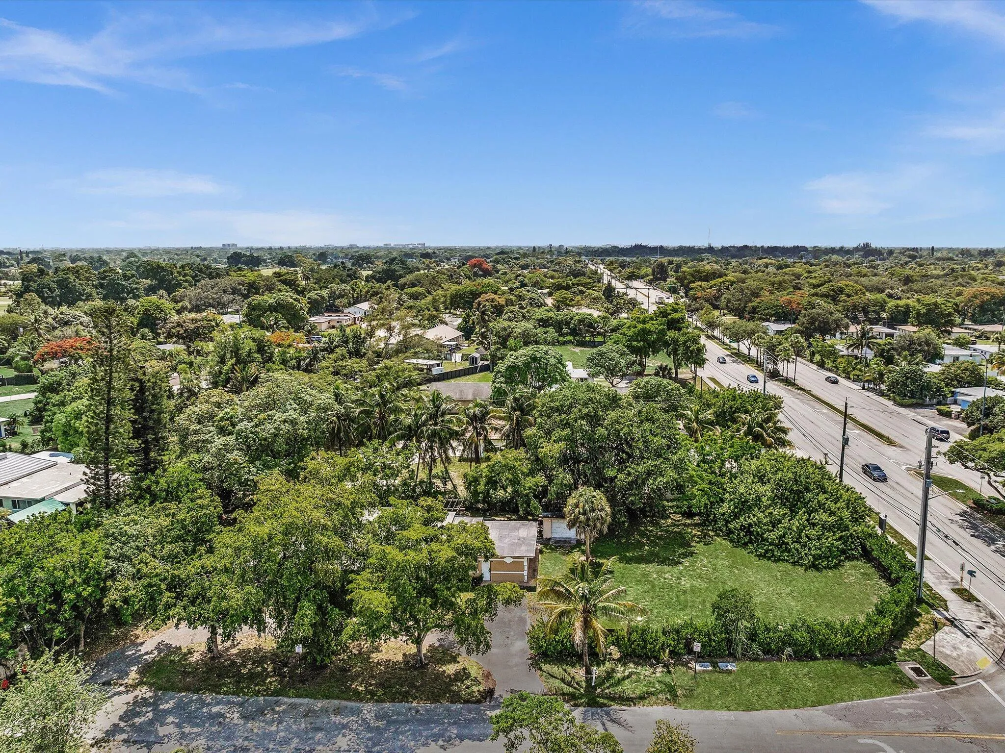 Expansive lot featuring mature trees, a grassy area, and paved road frontage