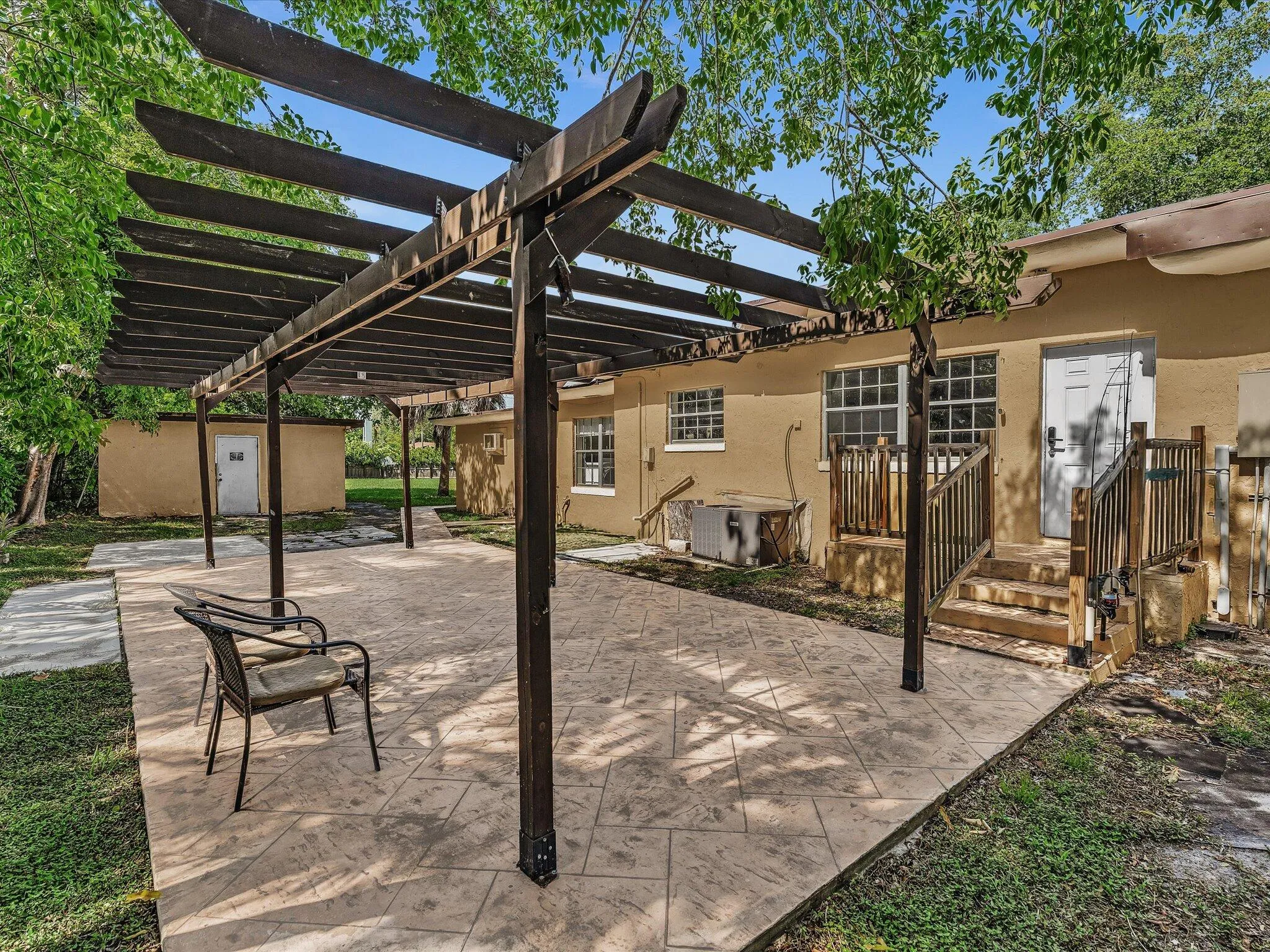 Expansive stamped concrete patio with an overhead pergola structure