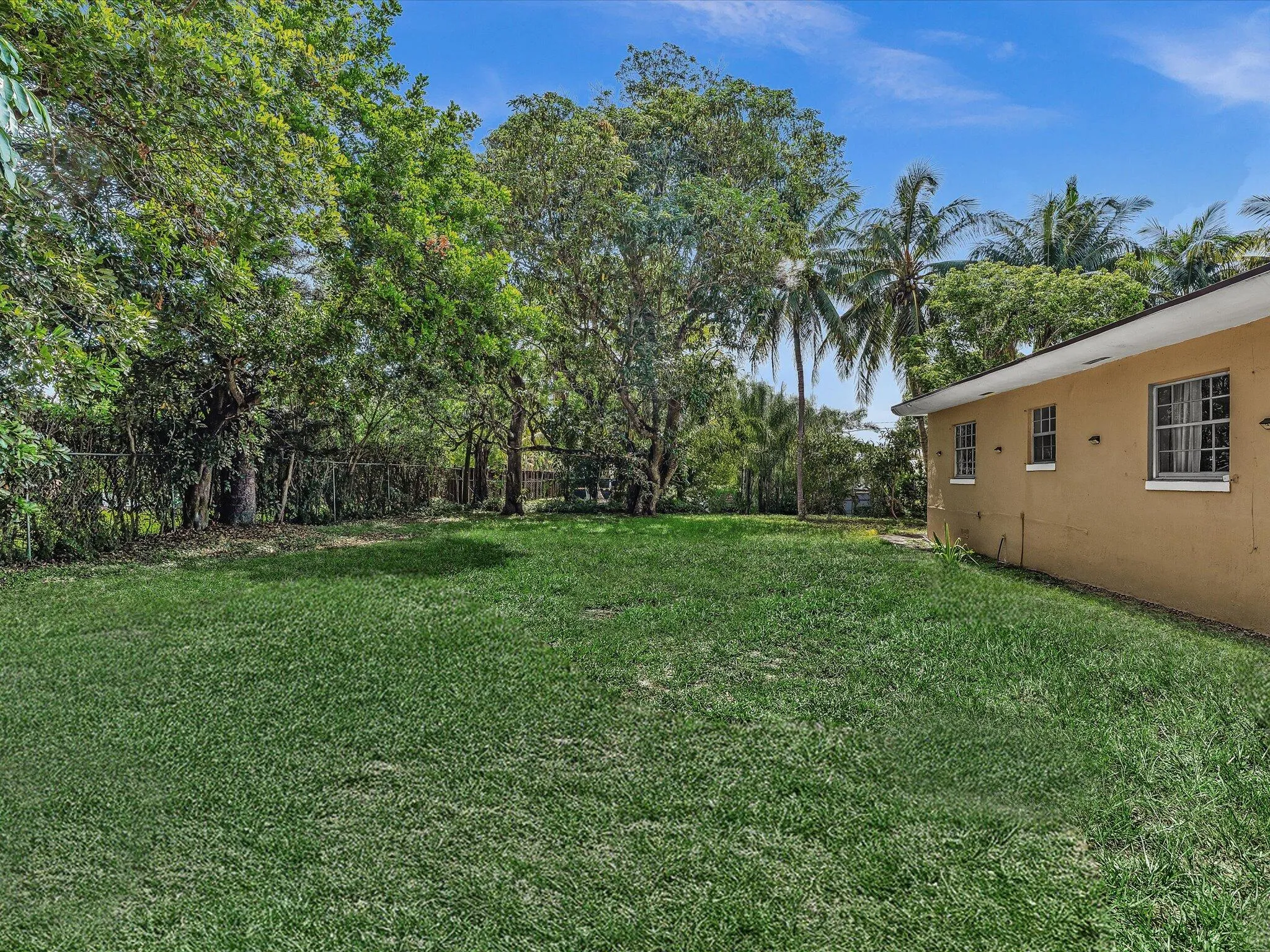 Expansive lawn with mature trees and perimeter fencing