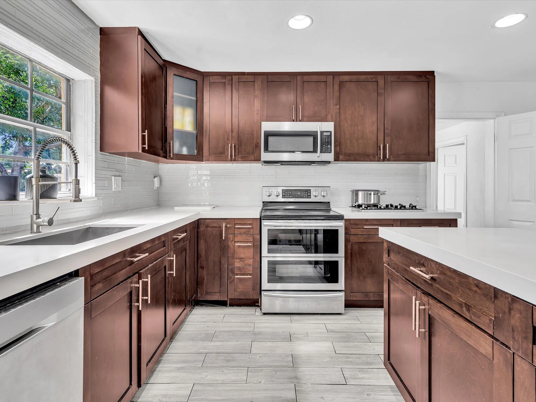Modern kitchen featuring rich wood-finish cabinetry, light countertops, and a subway tile backsplash