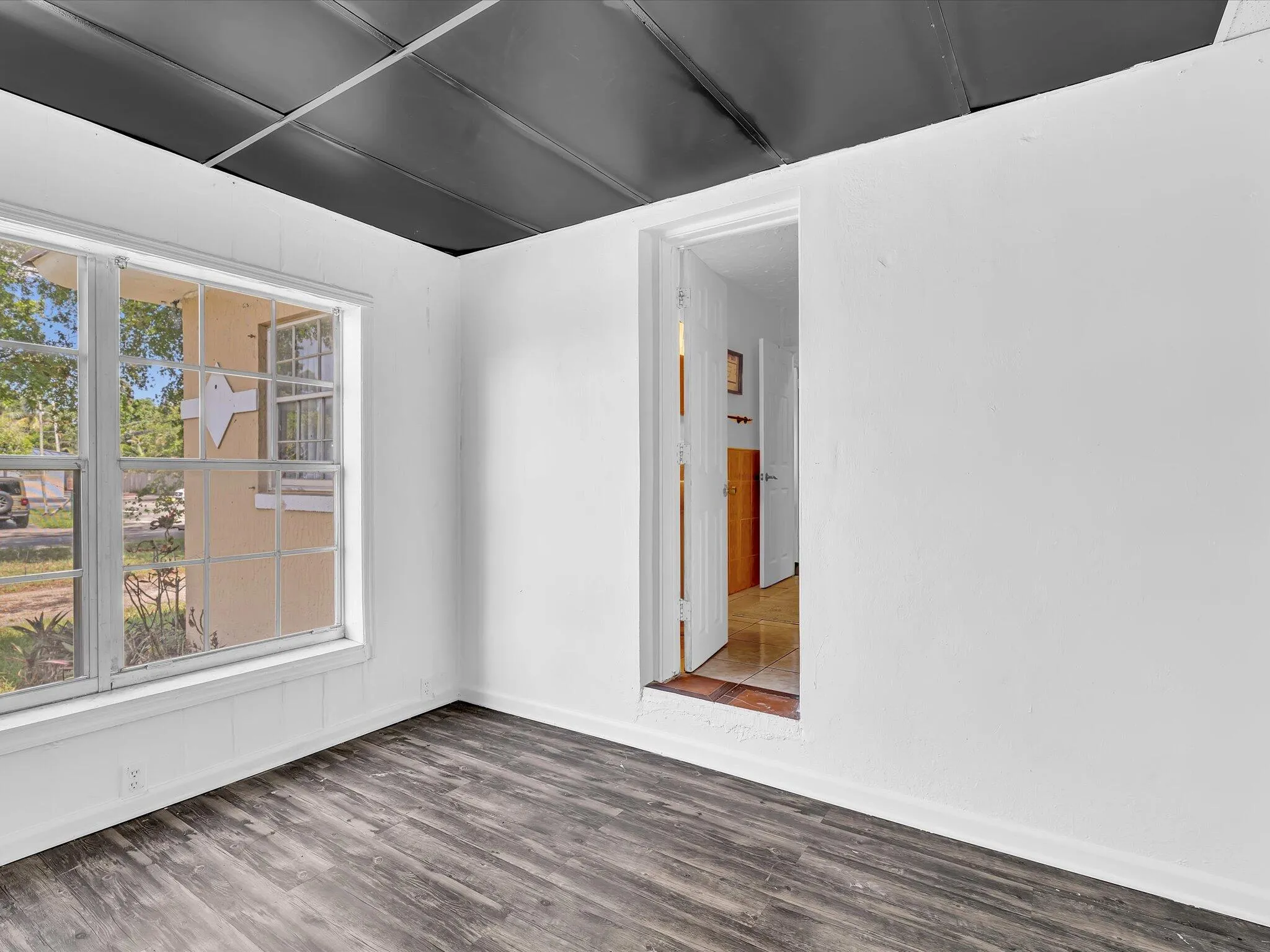 Interior room featuring wood-finish flooring, white painted walls, and a black panel ceiling