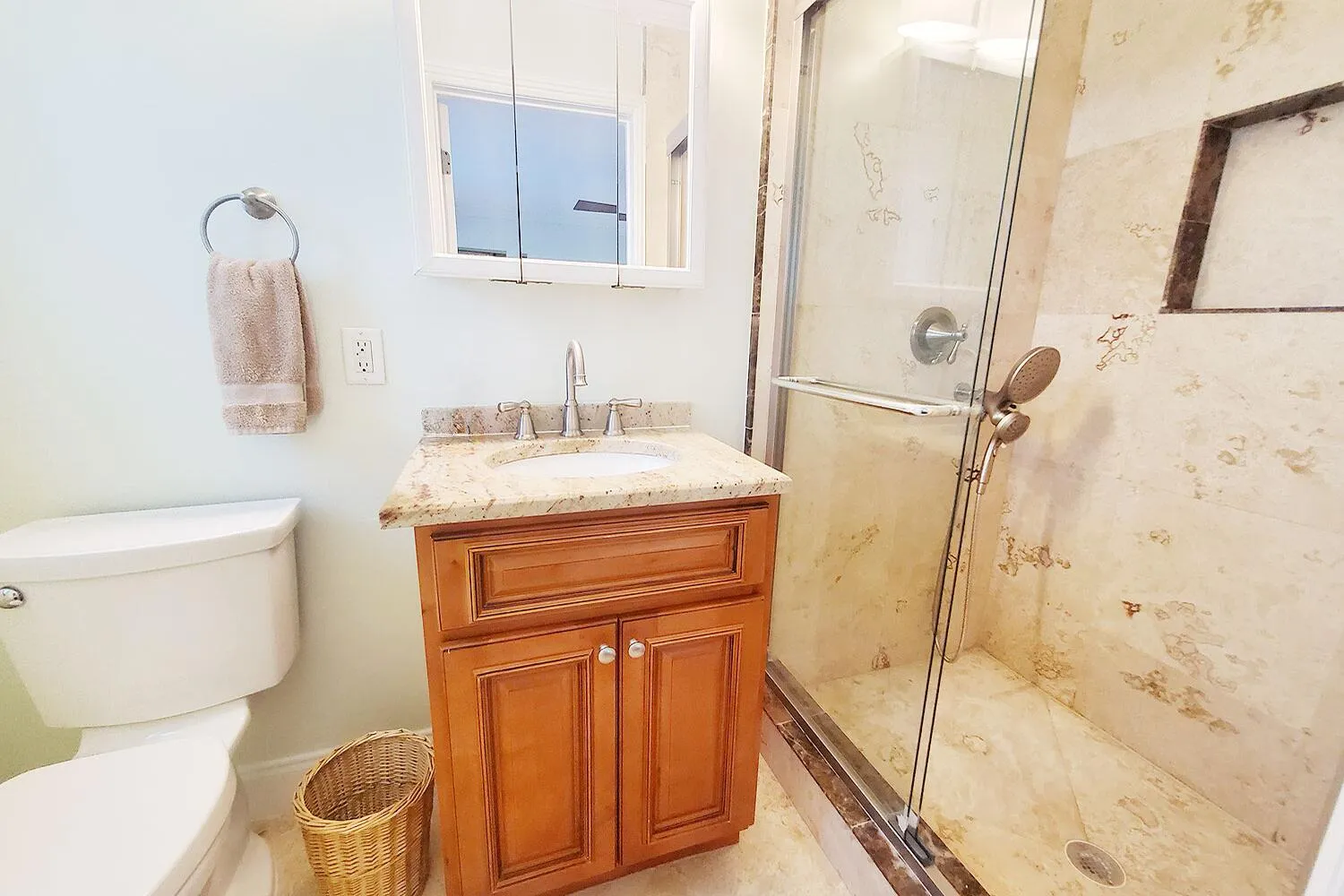 Bathroom featuring a glass-enclosed shower, a built-in shower niche, and a vanity with a granite countertop