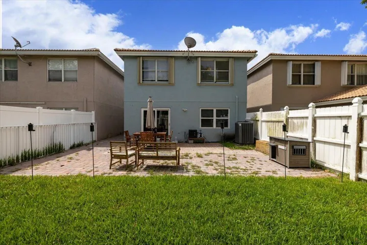 Spacious backyard featuring a paver patio with ample room for outdoor furnishings, an expansive lawn, and white privacy fencing