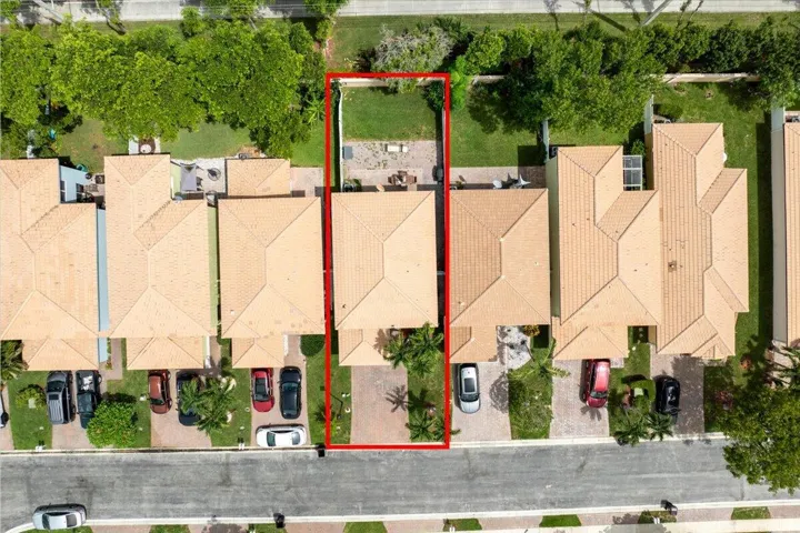 Aerial parcel view featuring a tiled roof structure, a paved driveway, and an exterior patio with a small lawn area