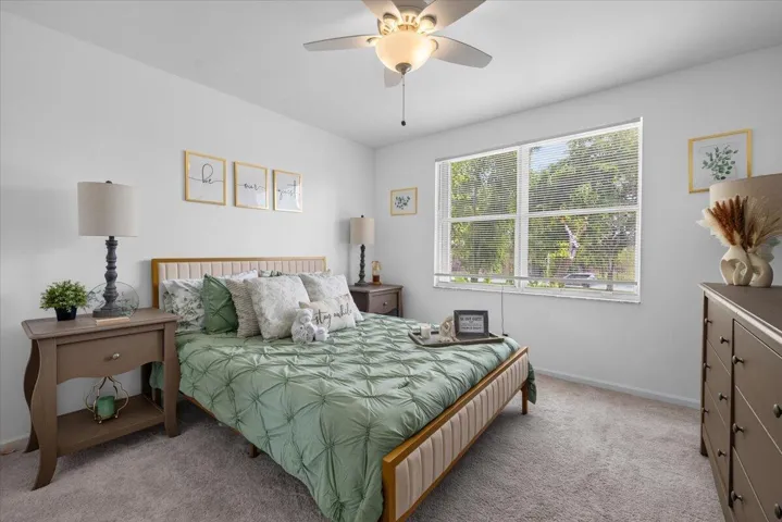 Carpeted room featuring a white ceiling and walls, a window with horizontal blinds, and a built-in ceiling fan with integrated lighting