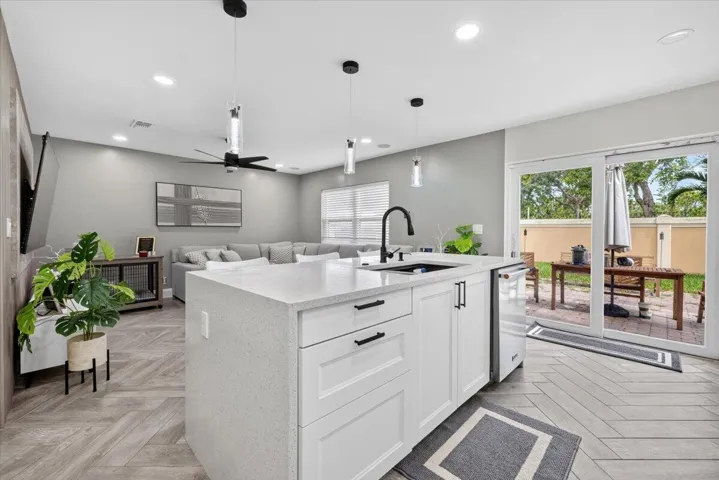 Open-concept interior featuring a kitchen island with white shaker cabinetry, an integrated dishwasher, and a matte black faucet