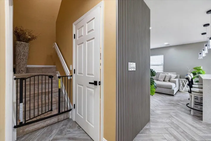 Entryway featuring a six-panel door with matte black hardware, vertical slatted accent wall, and wood-finish flooring in a herringbone pattern