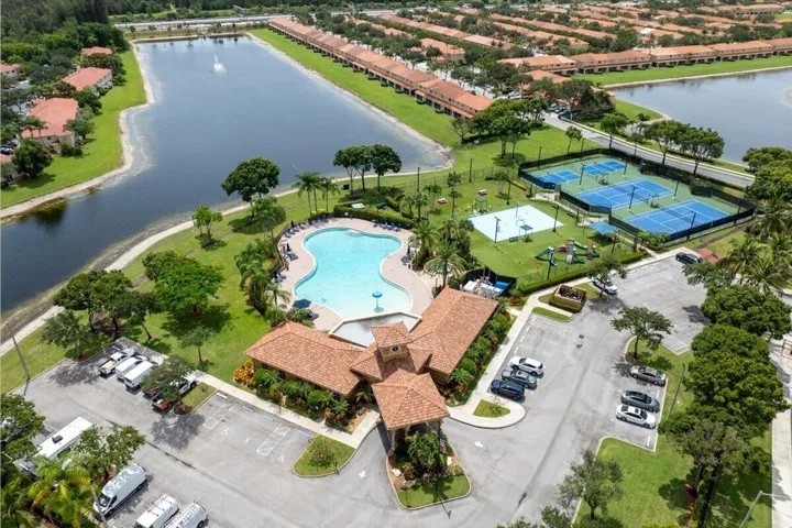 Community amenities featuring a clubhouse with a terracotta-style roof, a freeform swimming pool, multiple tennis courts, and a basketball court
