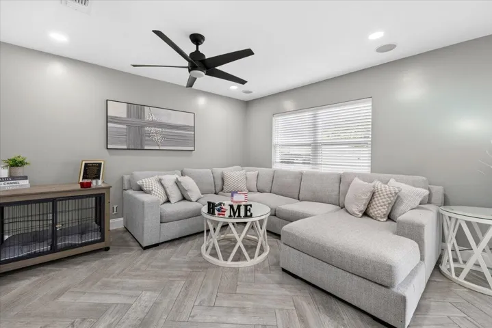 Living space featuring herringbone-patterned wood-finish flooring, recessed lighting, and a modern black ceiling fan