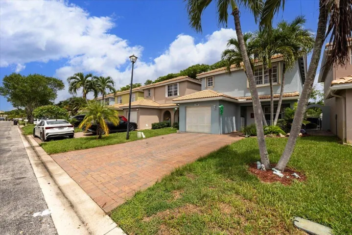 Two-story residence featuring a tile roof, light blue exterior, and a two-car garage