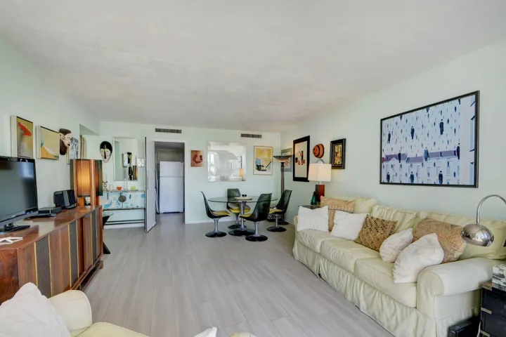 Open-concept living area with light wood-finish flooring, recessed lighting, and pale green walls