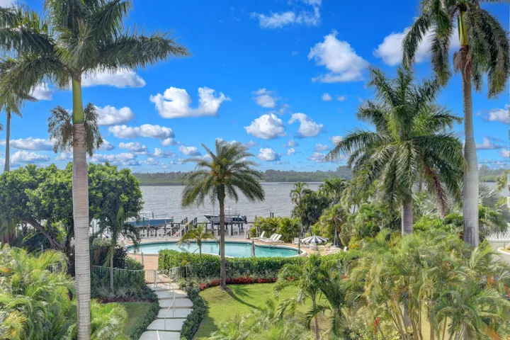 Lush tropical landscaping surrounds a waterside swimming pool and dock structure