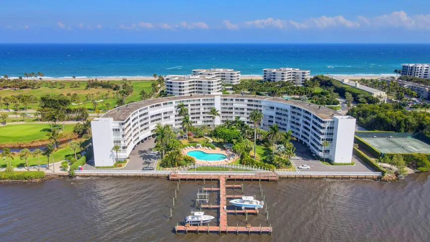 Curved multi-story building featuring extensive balconies, a central pool, and a private boat dock