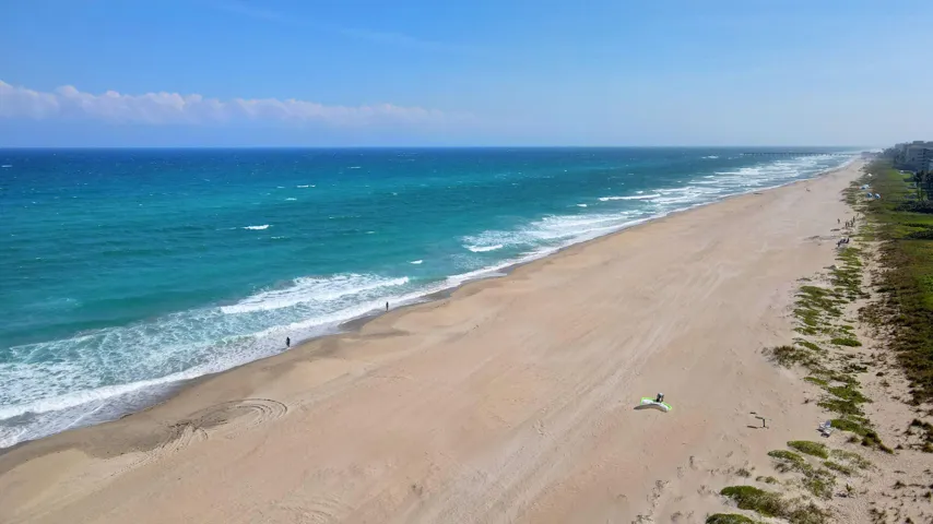 Expansive coastline featuring a sandy beach, deep blue ocean, and breaking waves