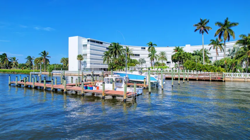 Waterfront property featuring a private dock system, multiple boat slips, and a multi-story building with extensive window lines
