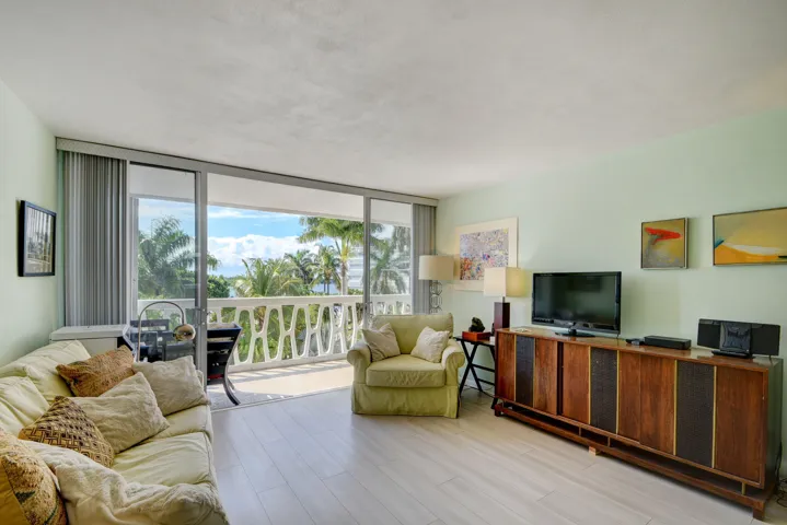 Expansive living area featuring light wood-finish flooring and a full-width sliding glass door opening to a private balcony