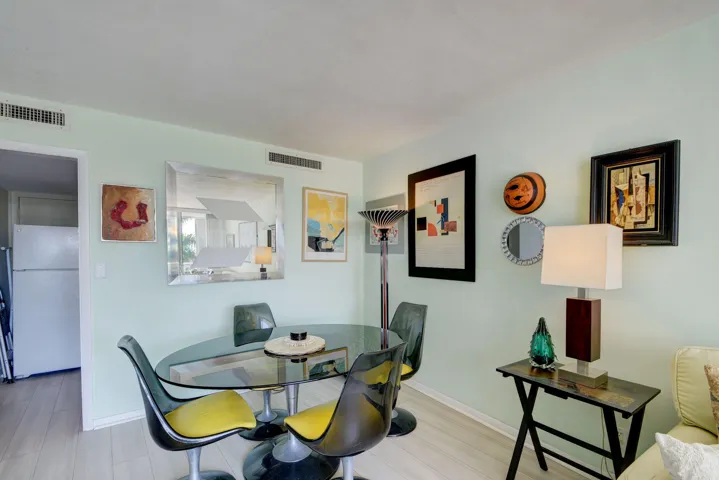 Dining area with light-toned flooring, featuring a glass-top table