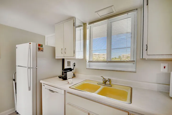 Kitchen featuring white cabinetry, a double-basin sink, white countertops, a built-in dishwasher, and a window with horizontal blinds