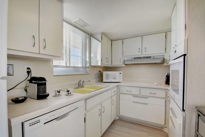 Kitchen featuring a double basin sink, built-in dishwasher, integrated wall oven, white cabinetry, and light-toned flooring