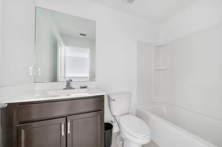Bathroom with a dark wood-finish vanity, integrated sink, and a large wall-mounted mirror