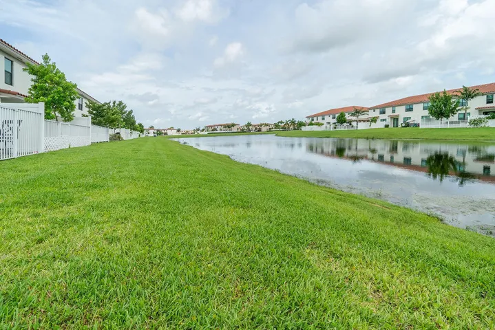 Expansive green space with lake view featuring partially white privacy fenced yard
