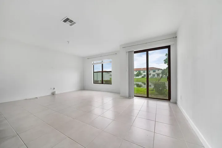 Spacious room featuring tile flooring, a large sliding glass door, and an additional window