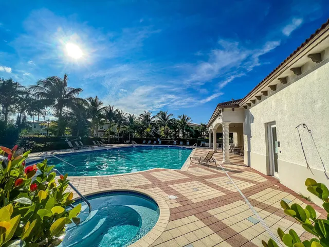 Resort-style pool area featuring a large swimming pool, integrated spa, and patterned paver decking