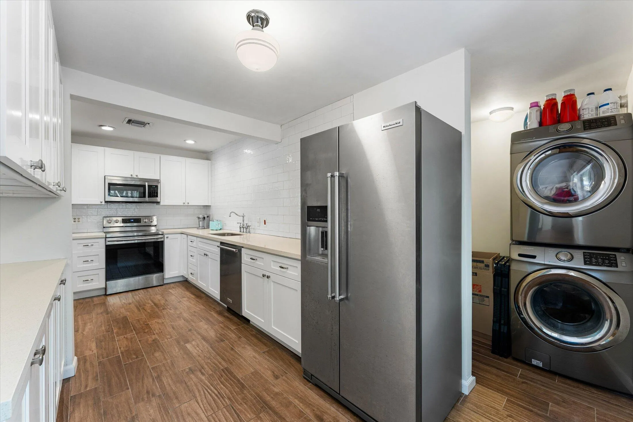 Kitchen with white cabinetry, stainless steel appliances, and wood-finish flooring