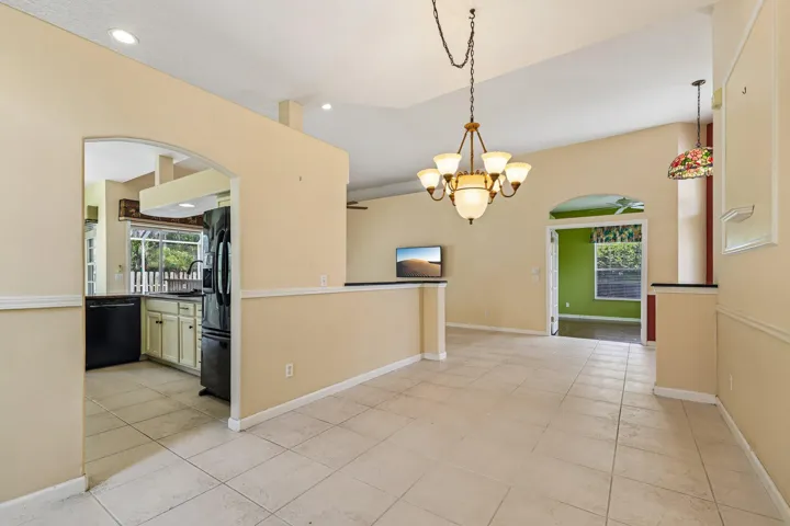 Open-concept living space with tile flooring, a vaulted ceiling, and an ornate chandelier