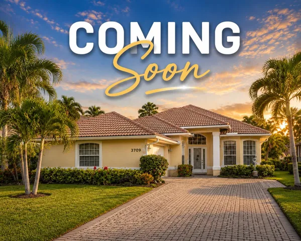 Exterior stucco residence featuring a tile roof, decorative landscaping, and a paver driveway