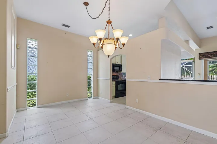 Spacious room featuring tile flooring, a vaulted ceiling, and an ornate chandelier