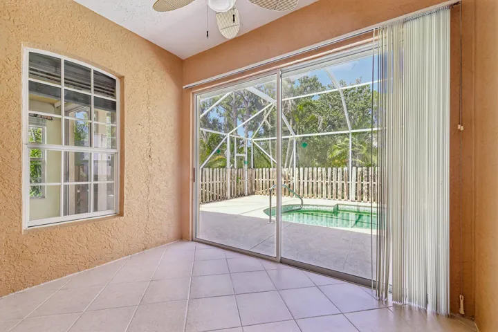 Indoor-outdoor space featuring large format tile flooring, a multi-pane arched window, and sliding glass doors
