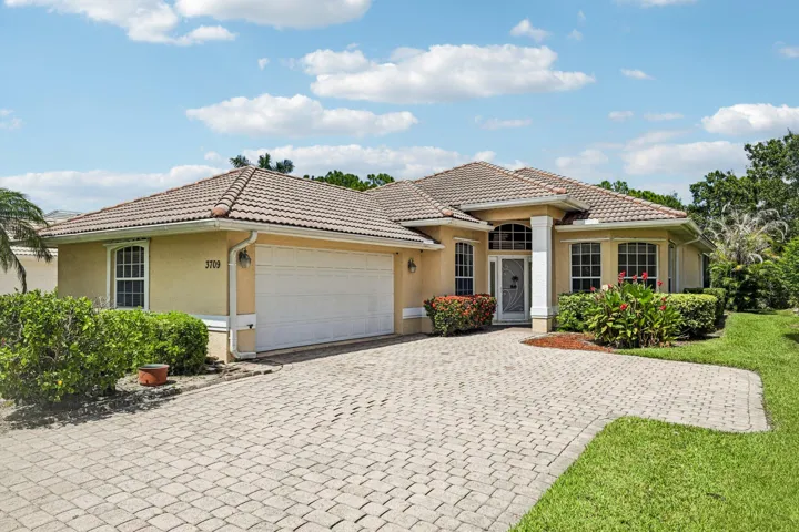 Mediterranean-style residence featuring a tile roof, stucco exterior, and a paver driveway