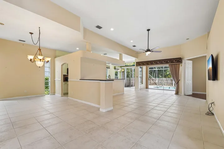 Spacious interior featuring tile flooring throughout, vaulted ceilings, and a built-in ceiling fan with integrated lighting