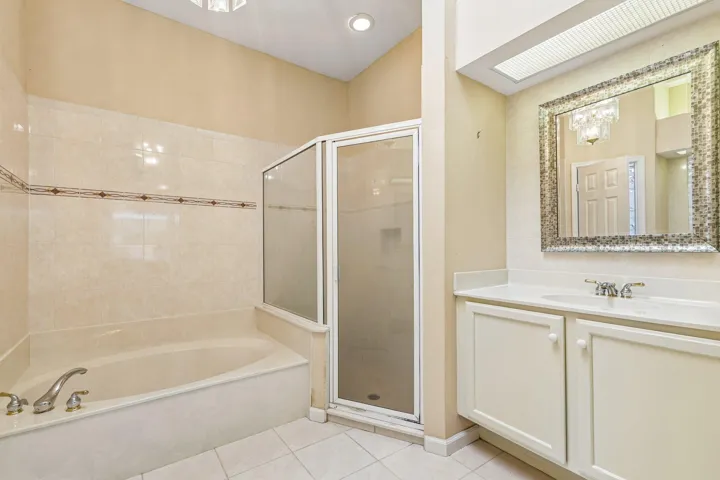 Bathroom with a built-in tub, tiled shower enclosure, white vanity with integrated sink, and an ornate framed mirror