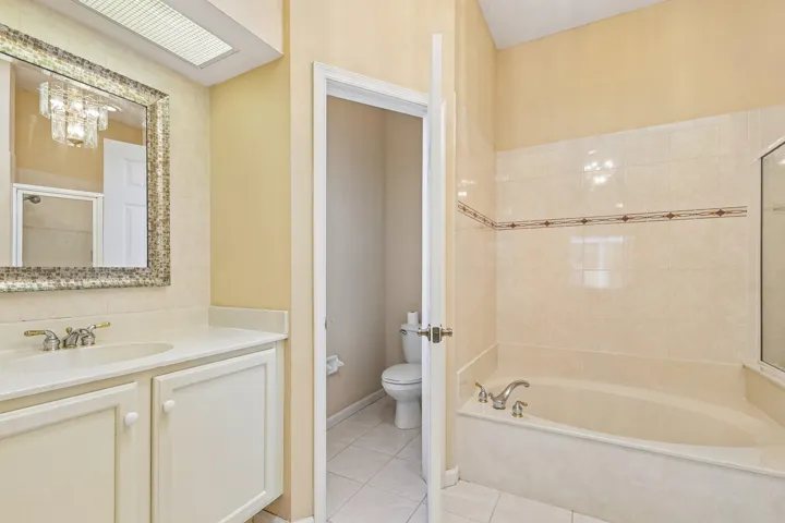 Bathroom featuring a built-in tub with tiled surround, a vanity with an integrated sink and storage, and a mosaic-framed mirror