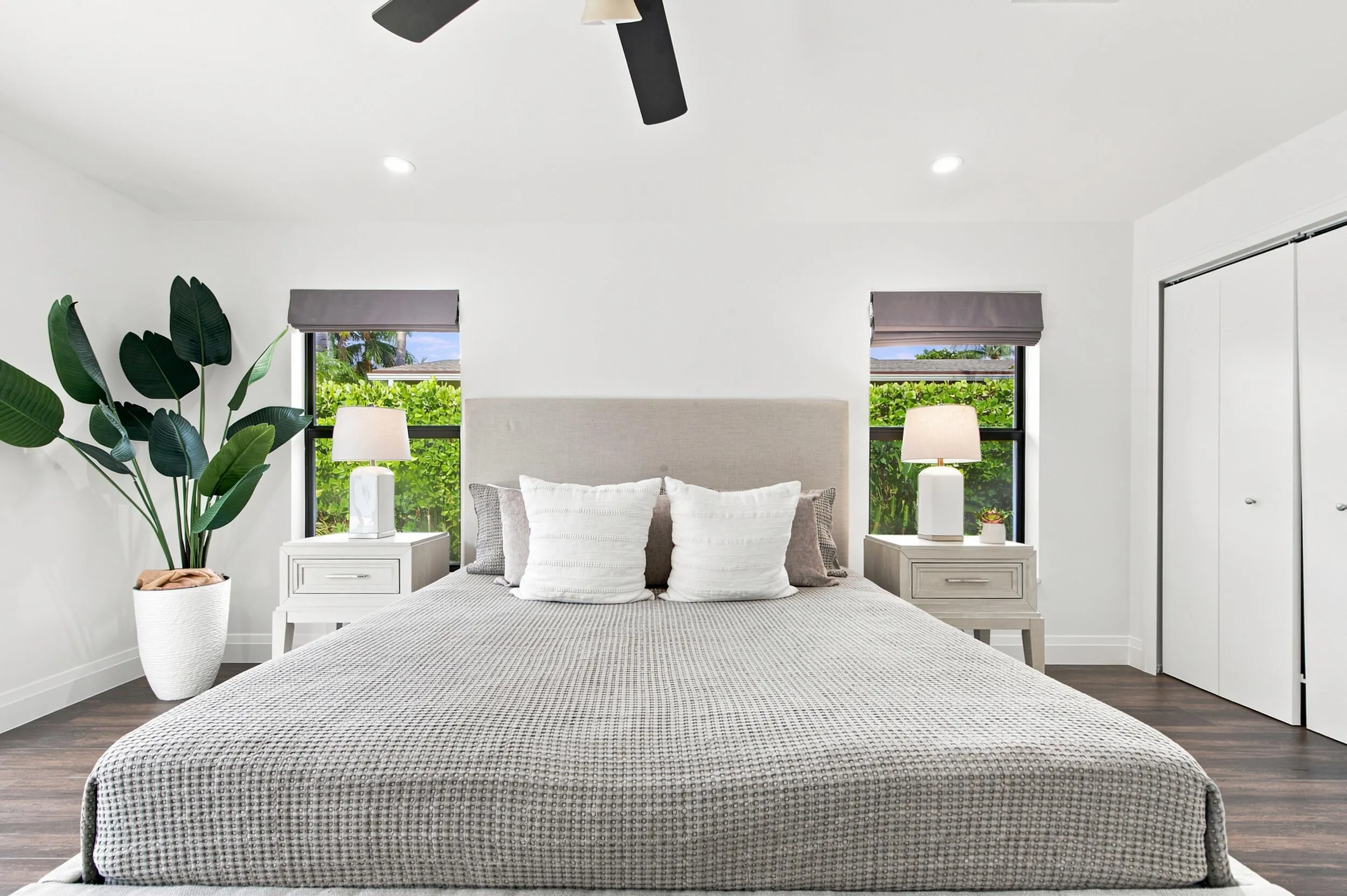 Bright bedroom featuring wood-finish flooring, two windows with window treatments, recessed lighting, and a ceiling fan