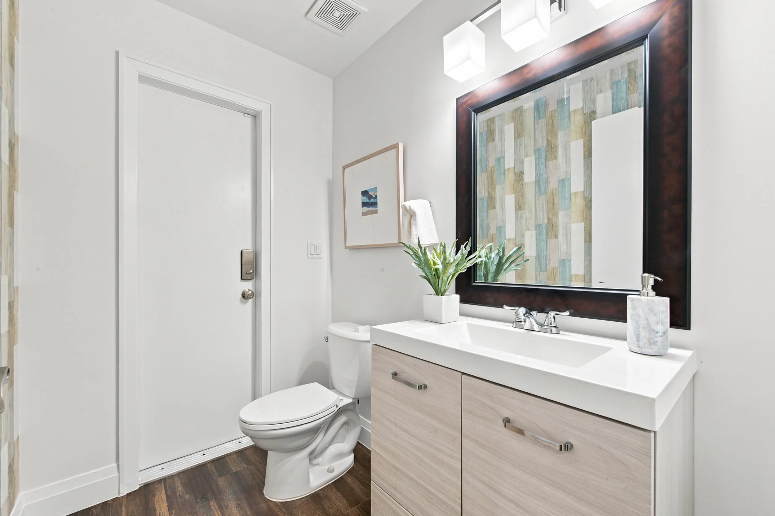 Bathroom featuring wood-finish flooring, a white toilet, and a vanity with a white countertop