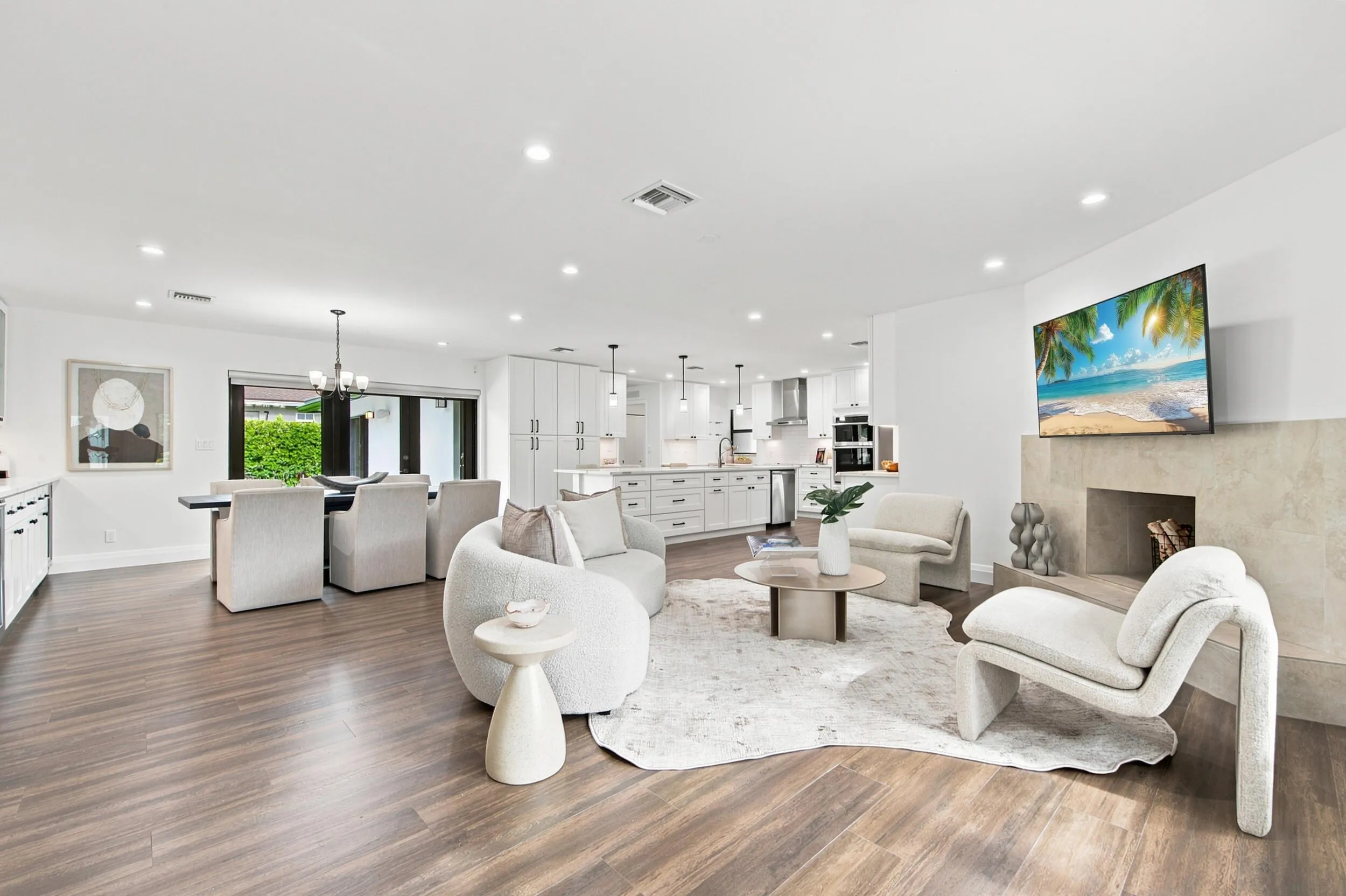 Open-concept living area featuring wood-finish flooring, recessed lighting, and a stone-clad fireplace